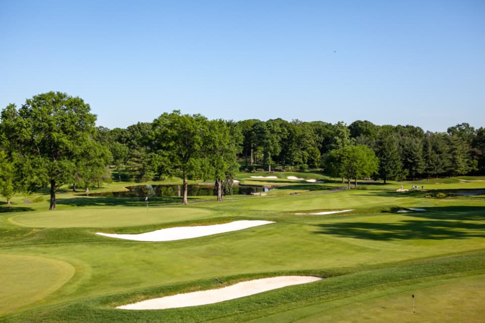 A wide fairway framed by trees and bunkers on a clear day